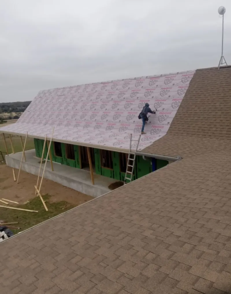 Worker preparing underlayment for a metal roof installation in Greenwood